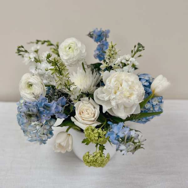 White and blue mixed flower arrangement in a white vase