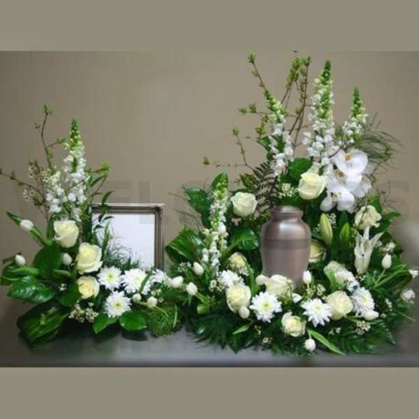 White floral funeral arrangement with a metal urn in the center