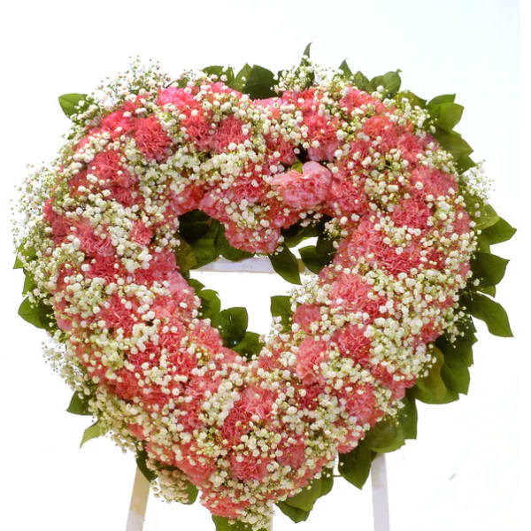 Heart-shaped pink floral wreath on a stand
