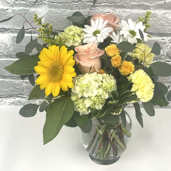 Mixed bouquet of yellow, pink, and white flowers in a glass vase