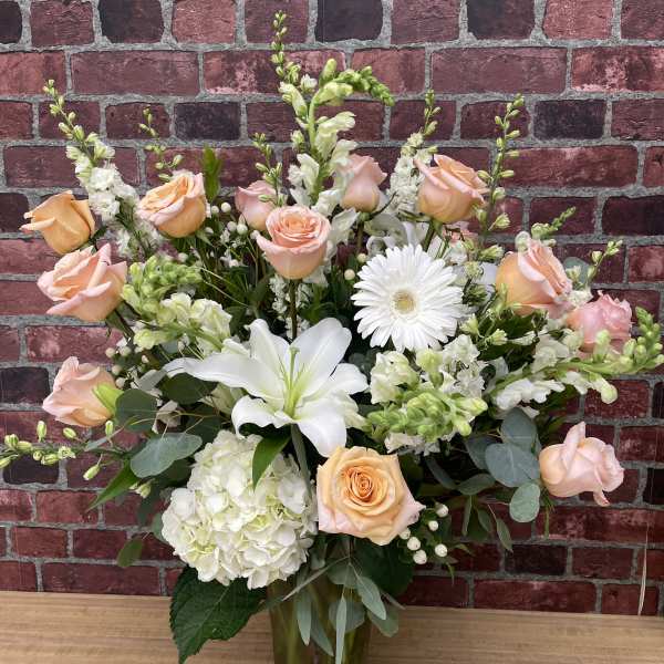 Peach roses and white lilies in a glass vase