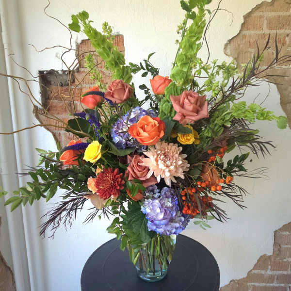 Mixed bouquet of roses, hydrangeas, and chrysanthemums in a glass vase