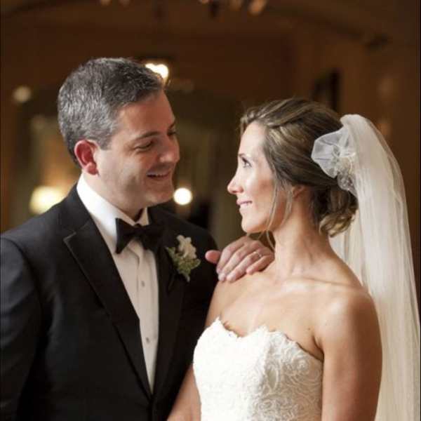 Bride holding a white bouquet beside a groom in a tuxedo