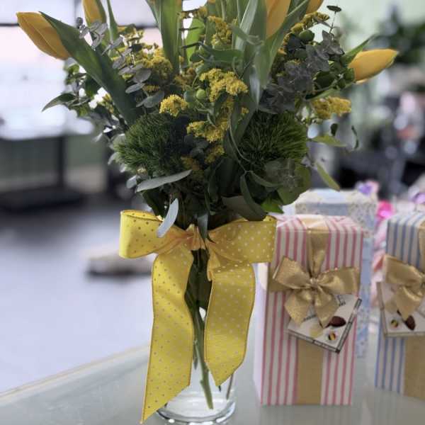 Yellow tulips in a clear glass vase with a yellow ribbon
