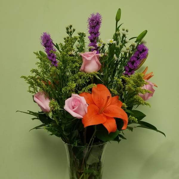 Bouquet of orange lilies and pink roses in a clear glass vase
