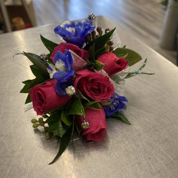 Small bouquet of pink roses and blue flowers with decorative accents