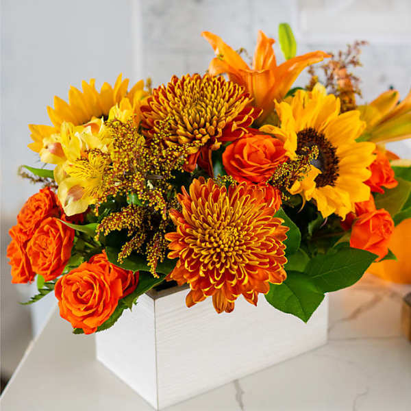 Orange and yellow flower arrangement in a white box