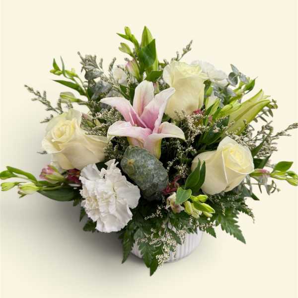 Bouquet of white roses, pink lilies, and white carnations in a vase