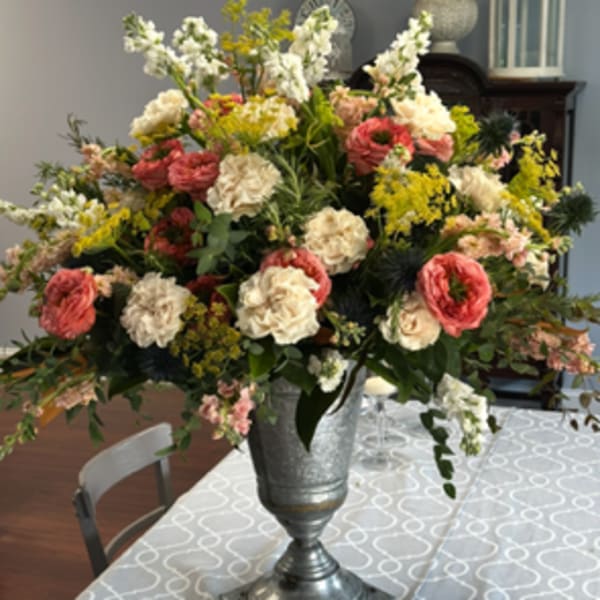 Large mixed floral arrangement in a silver urn on a table