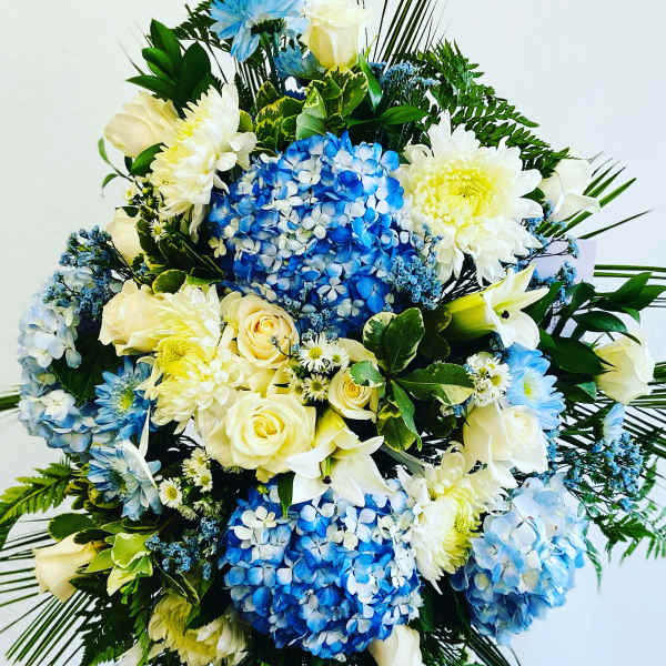 Blue and white floral spray with roses, hydrangeas, and chrysanthemums
