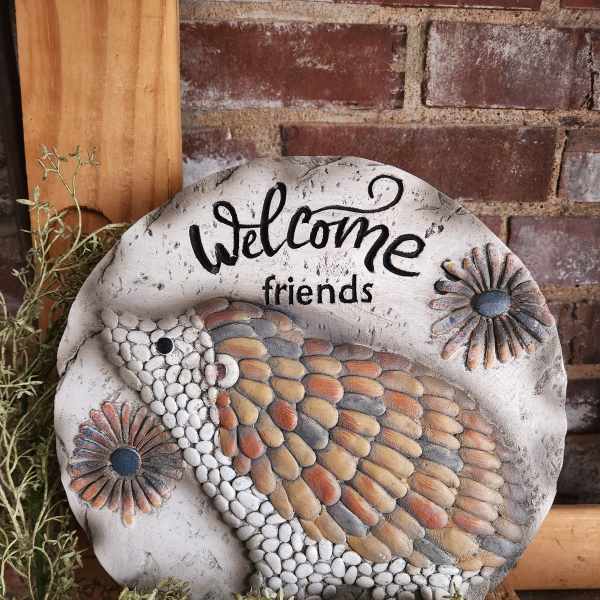 Round decorative stone plaque with a bird and "Welcome friends" text