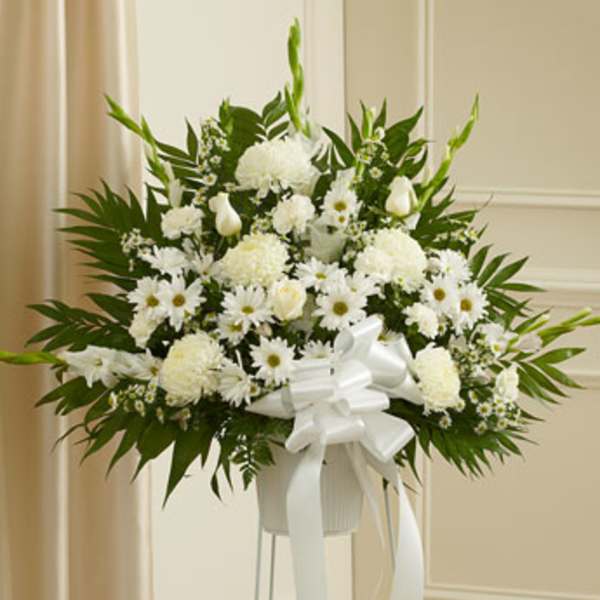 White floral standing arrangement with a ribbon on a pedestal