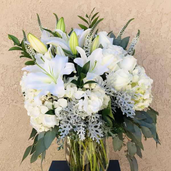 White lilies and roses arranged in a glass vase