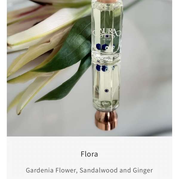 Perfume bottle beside a white flower and green leaves