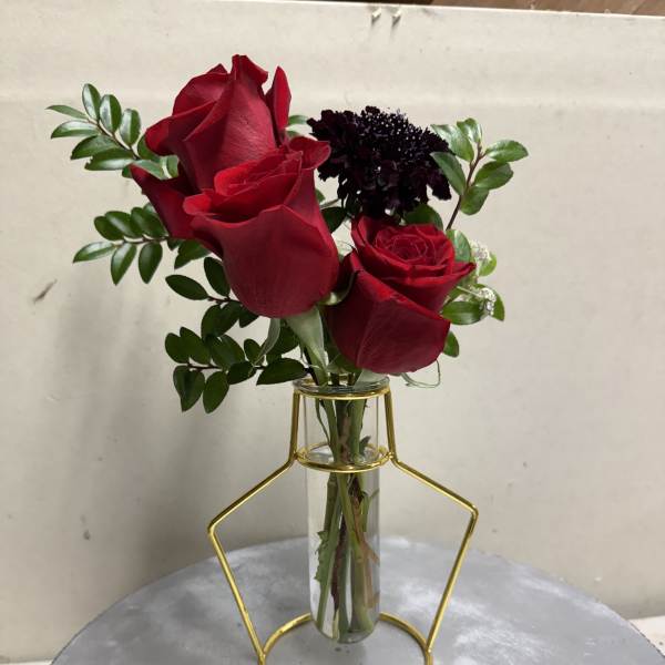 Red roses in a clear glass vase with greenery
