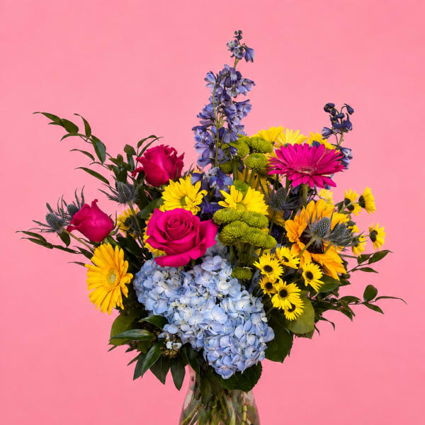 Colorful bouquet of roses, hydrangeas, and daisies in a glass vase