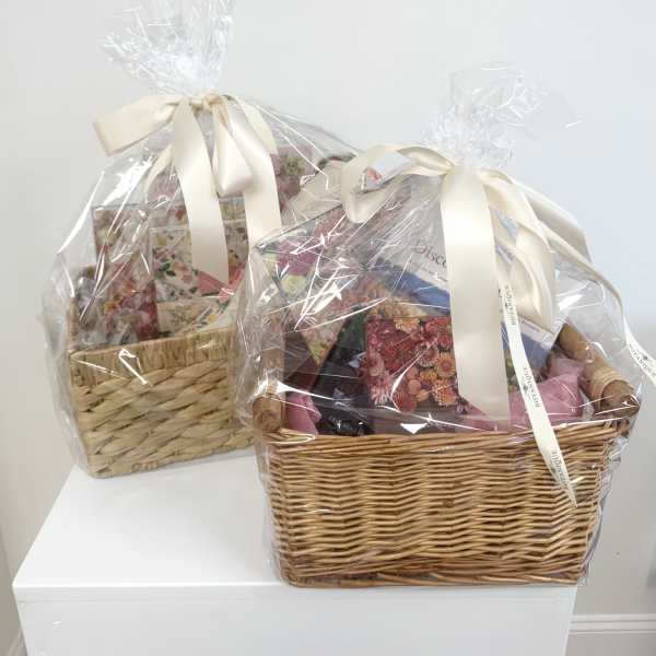 Two wrapped gift baskets with ribbon bows on a white surface