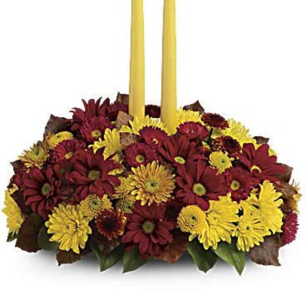 Red and yellow flower centerpiece with two tall yellow candles