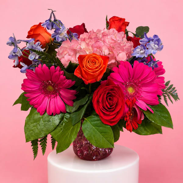 Mixed bouquet of roses, hydrangea, and gerbera daisies in a glass vase