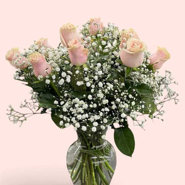 Pink roses and baby's breath arranged in a clear glass vase