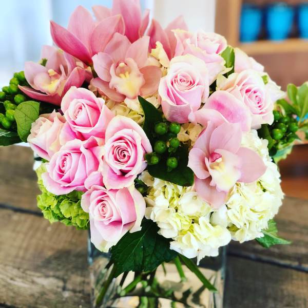 Pink roses and orchids arranged in a clear glass vase