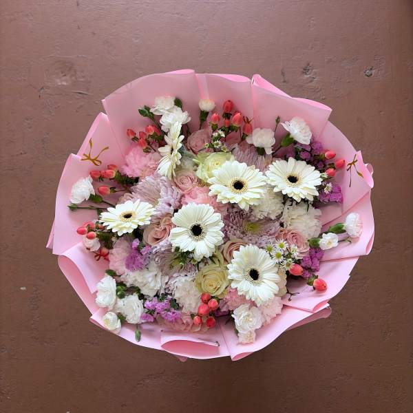 Pink-wrapped bouquet of white gerbera daisies and mixed pastel flowers