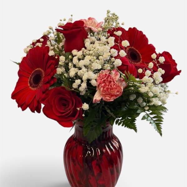 Red roses and gerbera daisies in a red glass vase
