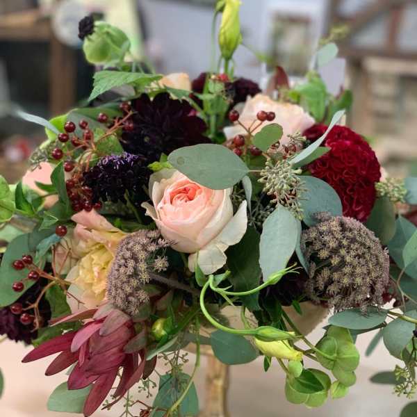 Mixed bouquet with a pale pink rose and burgundy blooms in a glass vase