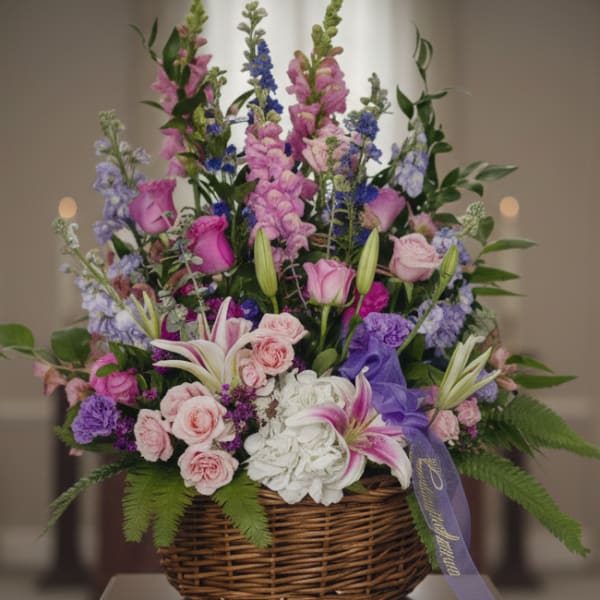 Basket arrangement of pink, purple, and white flowers with a ribbon