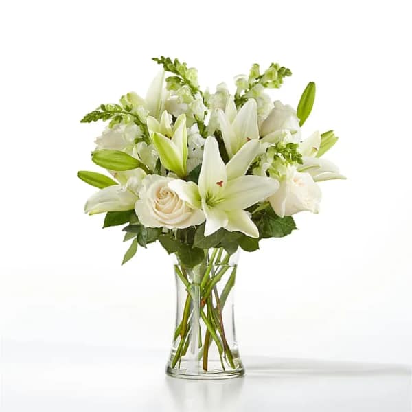 White lilies and roses arranged in a clear glass vase