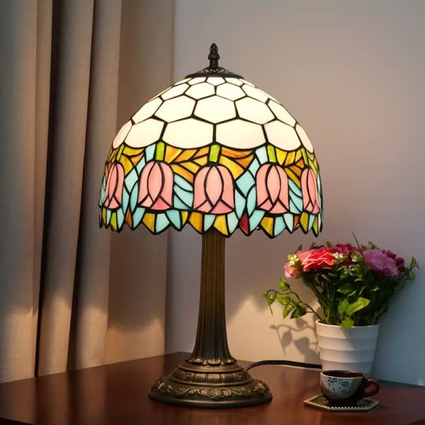 Stained-glass table lamp beside a small potted flower arrangement