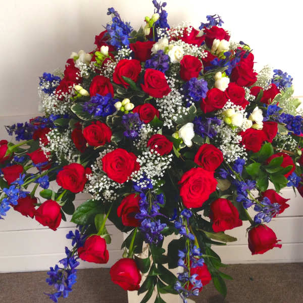 Large bouquet of red roses with blue flowers and white filler in a vase