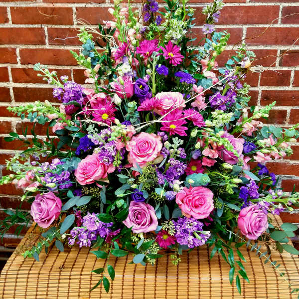 Large bouquet of pink and purple flowers arranged against a brick wall