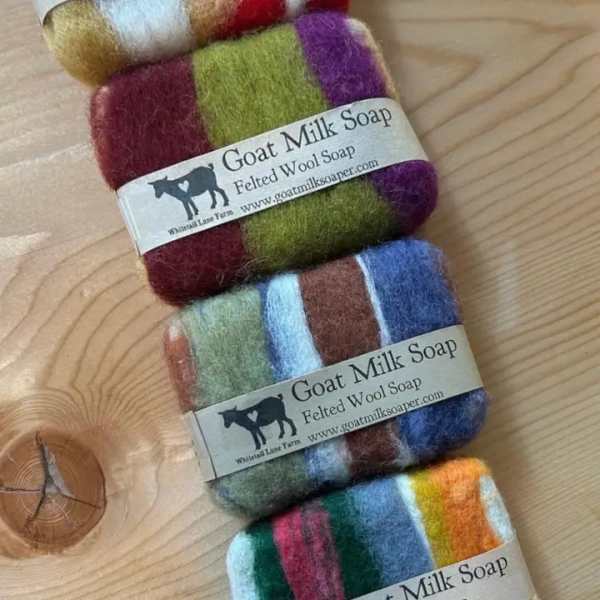 Stack of multicolored felted wool soap bars on a wooden surface