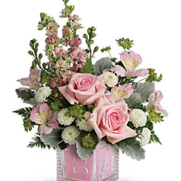 Pink roses and mixed blooms arranged in a clear square vase