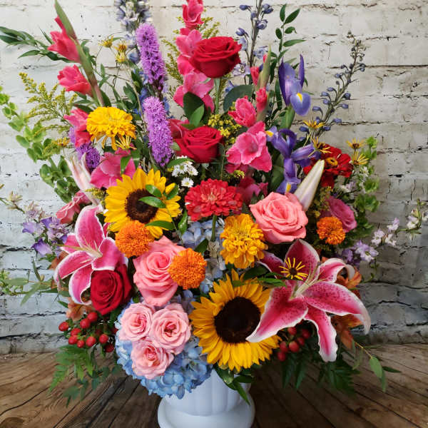 Large mixed flower arrangement in a white pedestal vase