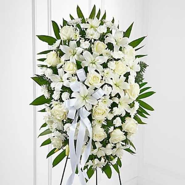 White funeral spray with lilies and roses on a standing easel