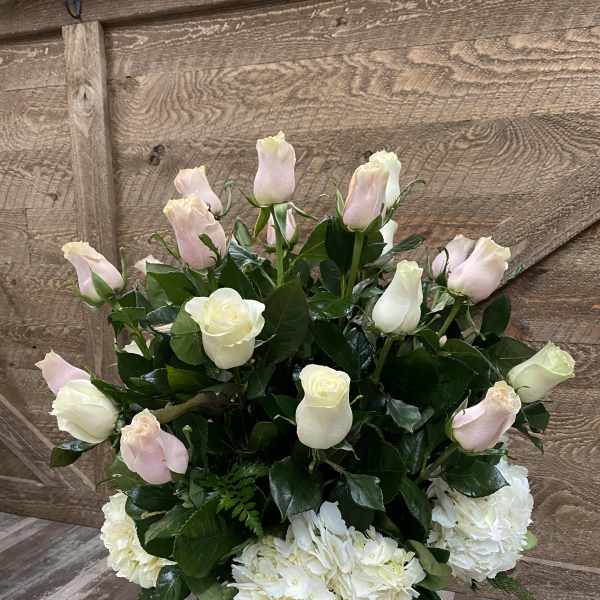 White and pale pink roses with white hydrangeas in a glass vase