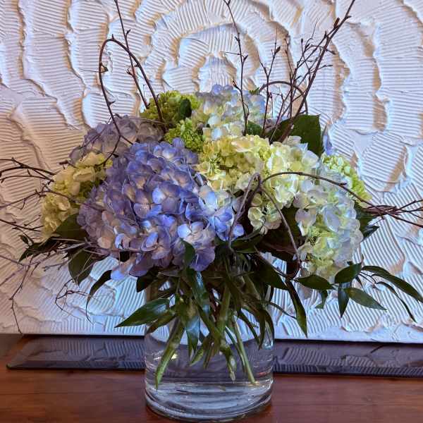 Blue and white hydrangea arrangement in a clear glass vase