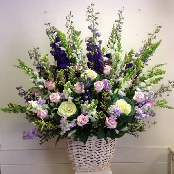 Large basket arrangement of pink and cream roses with purple and white spikes