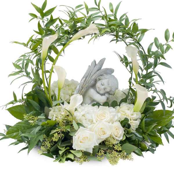 White roses and calla lilies arranged around a sleeping angel figurine
