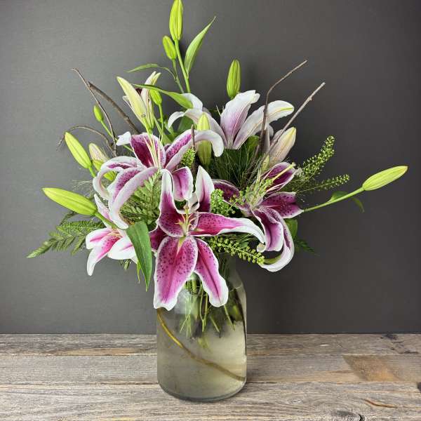 Pink and white lilies arranged in a glass vase