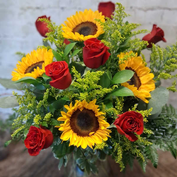 Bouquet of red roses and yellow sunflowers in a glass vase