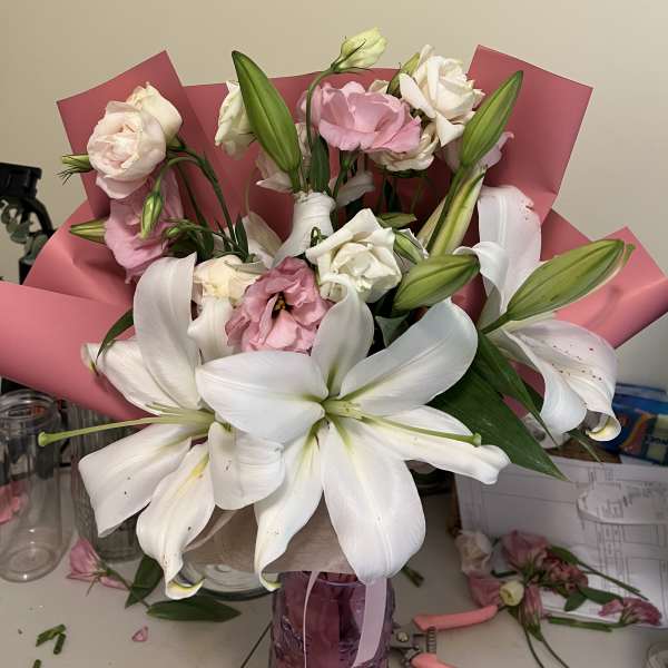 Bouquet of white lilies and pink roses wrapped in pink paper