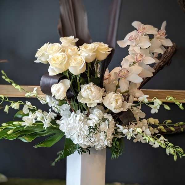 White roses and orchids arranged in a tall white vase