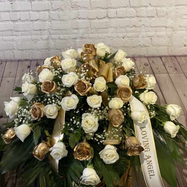 Large white and gold rose arrangement with a ribbon reading "Loving Angel"