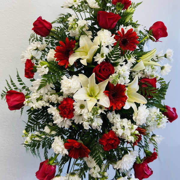 Standing floral spray with red roses, white lilies, and red and white daisies