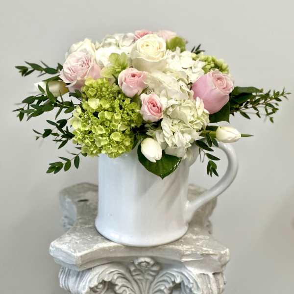 Pink and white roses with hydrangeas in a white mug vase