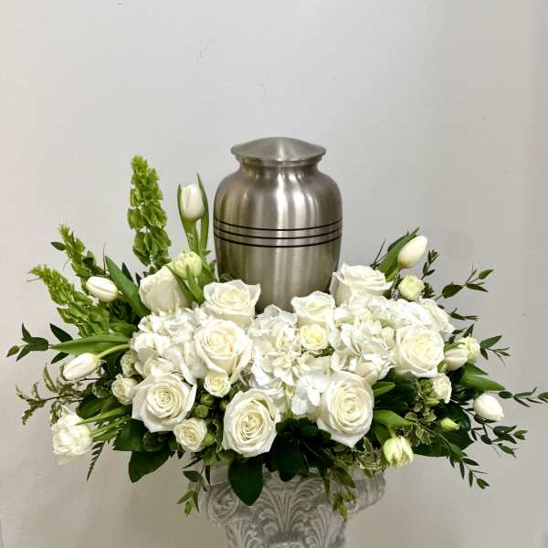White rose and tulip arrangement in a decorative urn with a silver urn behind it