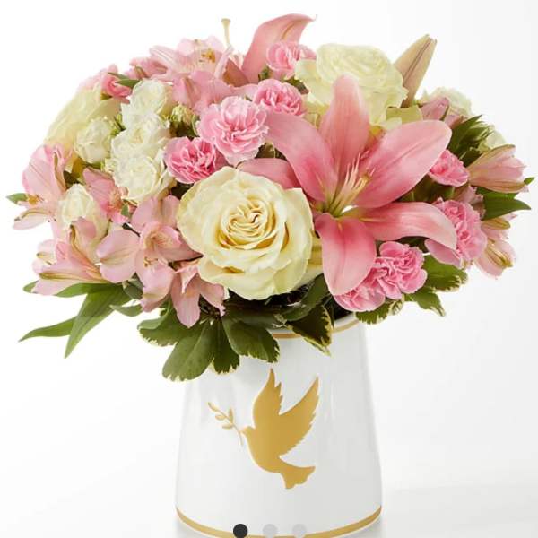 Pink and cream bouquet in a white vase with a gold dove design